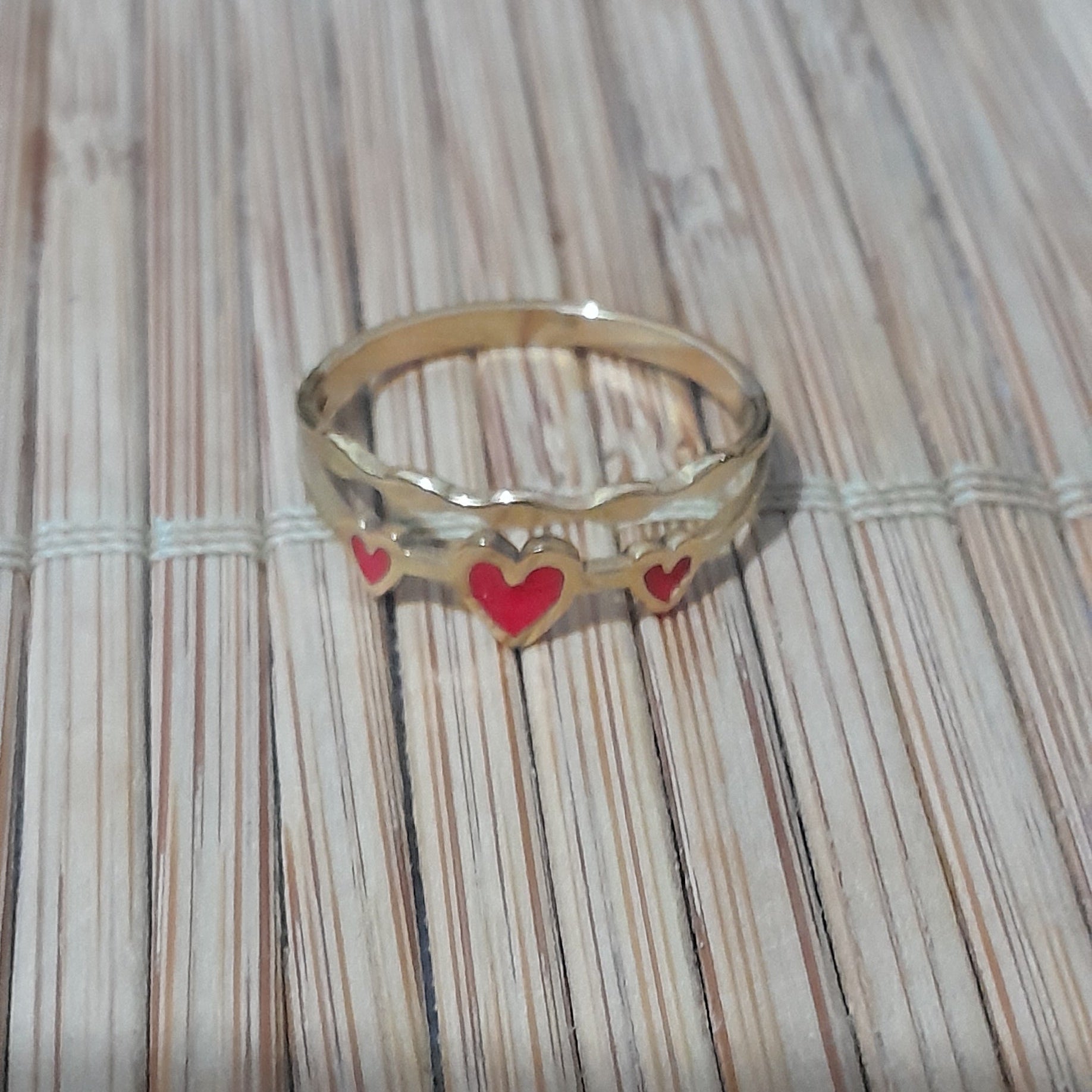 Anillo dorado con corazones rojos en esmalte