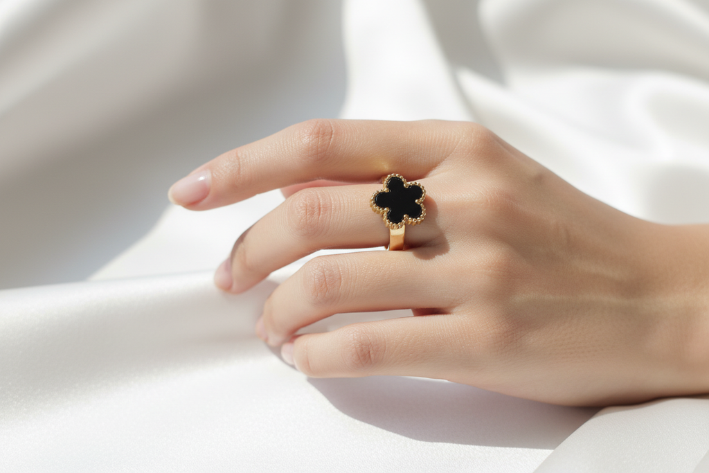 Anillo trébol negro dorado en mano delicada