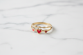 Anillo dorado corazones rojos sobre mármol
